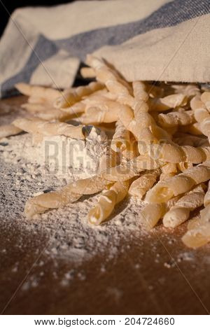 Homemade pasta lying on a wood cutting board partially covered with a cloth