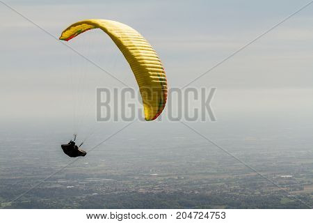 A para-glider up in the sky during a fly with the campaign below him as background
