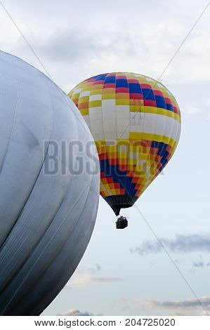 Two hot hair balloons flying in a cloudy sky