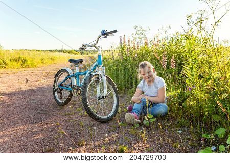 Beautiful smiling girl issitting near the bicycle in the park
