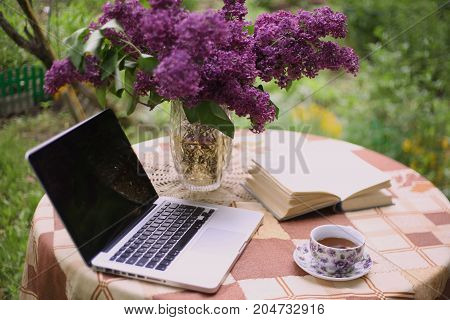 Laptop, China Teacup Book And Lilac Bouquet In Vase