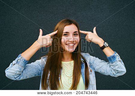 Girl fingers near the temples in the form of pistols, the girl smiles, brunette