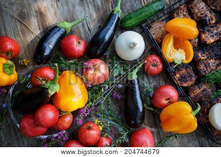 High Angle View of Grilled Meal of Steak, Chicken and Vegetables Spread Out on Rustic Wooden Table at Barbeque Party. Grilled meat and vegetables on rustic wooden table. Summer picnic time.