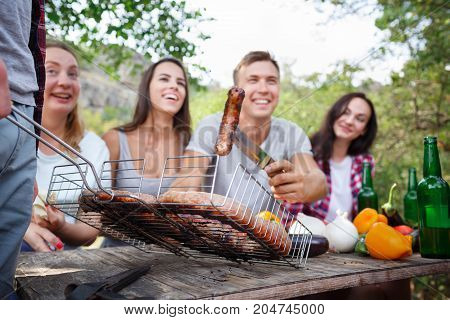 Romantic picnic. Group adult friends enjoying a healthy outdoor meal sitting together at a table in a lush green garden laughing and joking. Friends Outdoors Nature Picnic Chilling Out Unity Concept.