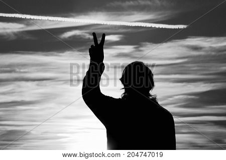 a woman giving a peace sign at sunset black and white.