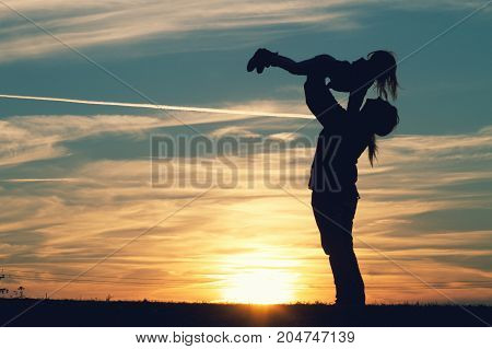 a mother with her child embracing at sunset.