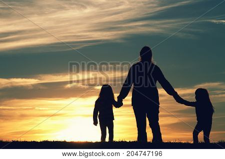 a mother walking with her children at sunset.