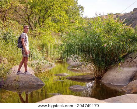 Overcoming the forest river. A man climbed out in the summer in the open air.