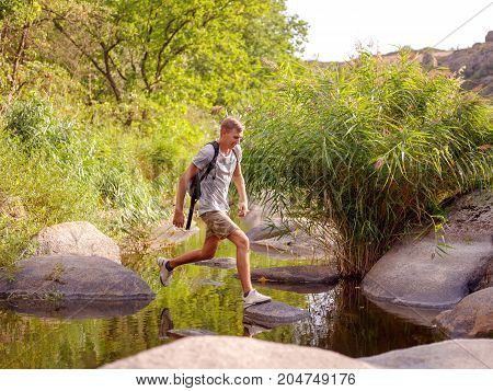 Overcoming the forest river. A man climbed out in the summer in the open air.