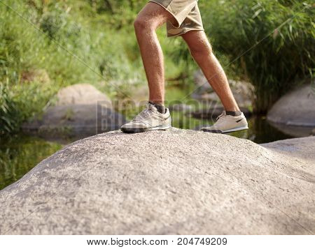 Overcoming the forest river. A man climbed out in the summer in the open air.