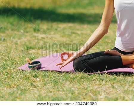 Close-up image of body parts girl's meditation at the health club outside with personal trainer, learning the correct form.
