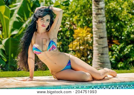 beautiful girl with long black hair lounging poolside