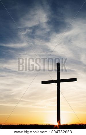 a christian cross silhouette at sunset with copy space.