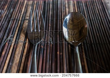 Close-up fork with spoon on wooden tablemat
