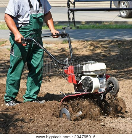 Gardener works with a tiller machinery in the park