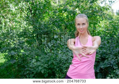 Portrait of sporty woman doing stretching exercises in park before training. Female athlete preparing for jogging outdoors. Runner doing side lunges. Sport active lifestyle concept. Full length