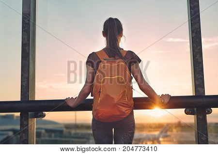 Girl at the airport window looking outside
