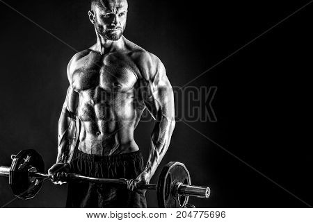 Studio portrait of topless bodybuilder performing biceps exercise with concentrated face over black background with smoke and light. Cutout.