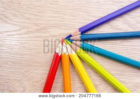 Different colored pencils photo with space for text. Seven pencils of rainbow colors lie on the table. Copyspace. Back to school. Wooden background.