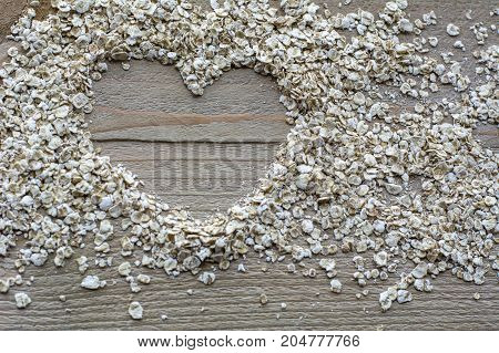 Many brown raw cereals in heart form are on the wooden background