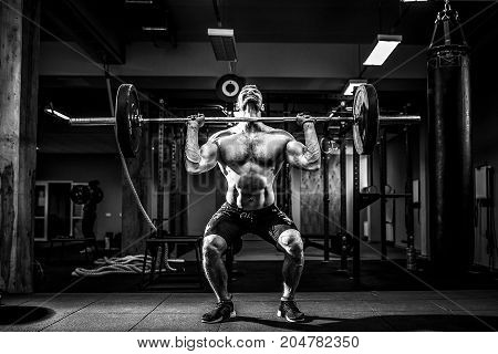 Muscular fitness man doing deadlift a barbell over his head in modern fitness center. Functional training. Snatch exercise