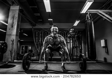 Muscular fitness man doing deadlift a barbell over his head in modern fitness center. Functional training. Snatch exercise