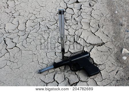 Parched ground and butterfly knife and gun/This is a detail of parched ground-dry puddle with butterfly knife and gun.