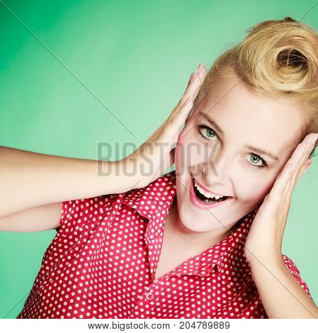 Shocking amazed astonished gestures concept. Shocked lovely pin up young girl holding head with hands. Studio shot on green background