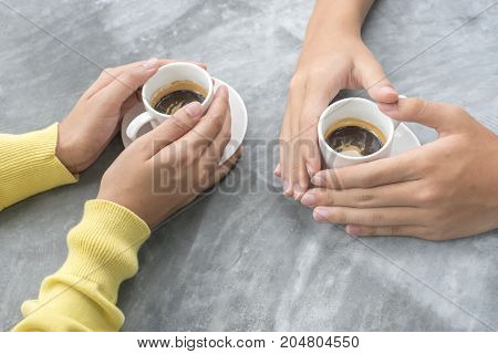 Close-up young couple is holding hands and coffee cup on the table.