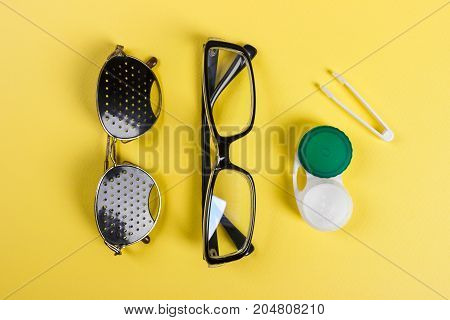 A set of accessories for sight. Pinhole glasses lenses with container and glasses for sight. Pair of medical pinhole glasses with reflections. Medical concept. Top view.