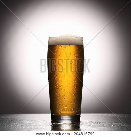 Glass Of Fresh Lager Beer On Light Studio Background With Reflection.