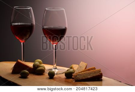 Wineglasses With Red Wine On Wood With Cheese And Green Olives. Studio Background