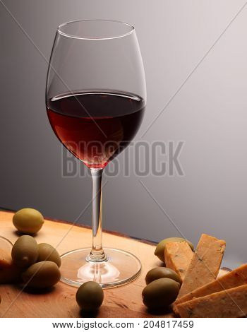 Wineglasses With Red Wine On Wood With Cheese And Green Olives. Studio Background