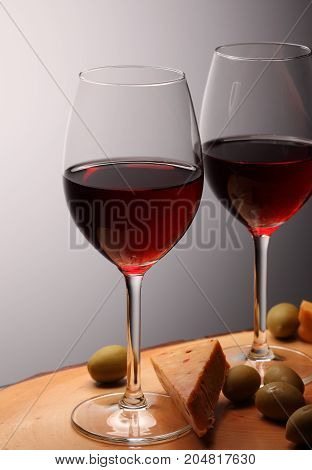 Wineglasses With Red Wine On Wood With Cheese And Green Olives. Studio Background