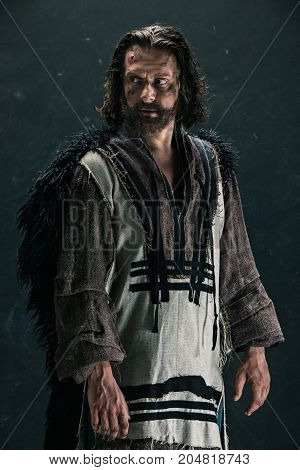 Actor in makeup, a poor man on black studio background. The bum in canvas rags. concept of vagrancy and survival
