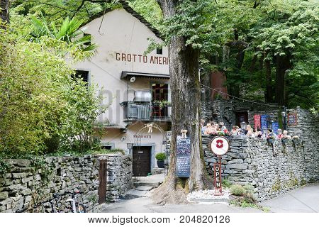 Ponte Brolla Switzerland - 30 July 2015: People eating on a Grotto a typical restaurant on the italian part of Switzerland at Ponte Brolla on Maggia valley