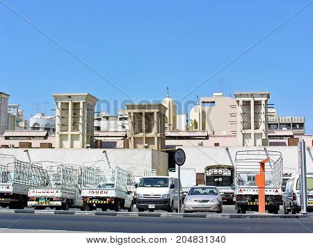 Dubai, United Arab Emirates - July 05, 2004: Cars park along houses that still have traditional windtowers for ventilation and air conditioning.