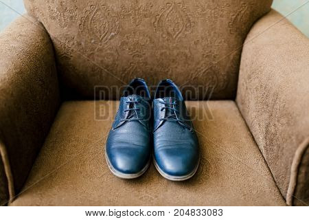 Groom's blue shoes on a brown armchair. Wedding concept. Artwork, soft focus. Top view