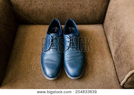 Groom's blue shoes on a brown armchair. Wedding concept. Artwork, soft focus. Top view