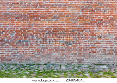 Horizontal Image Of Massive Red Brick Wall Pictured In Sunlight Lined With Thin Stripe Of Green Fres