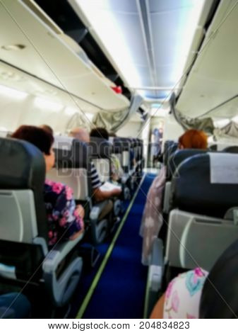 Blured view of the interior of modern commercial airplane with passengers on their seats waiting to taik off.