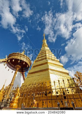 Wat Phra That Cho Hae Buddhism Temple with golden pagoda on blue sky background. Places worship of buddhists and attractions famous religion at Phrae Province Thailand