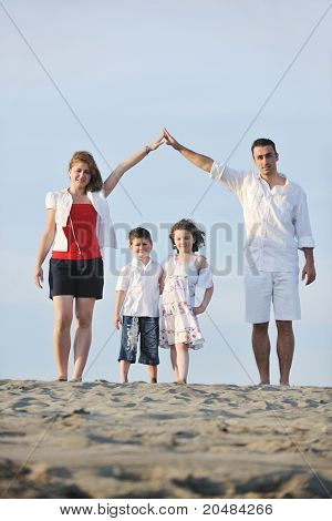 happy young family have fun on beachand showing home sign with conncected hands while protecting childrens