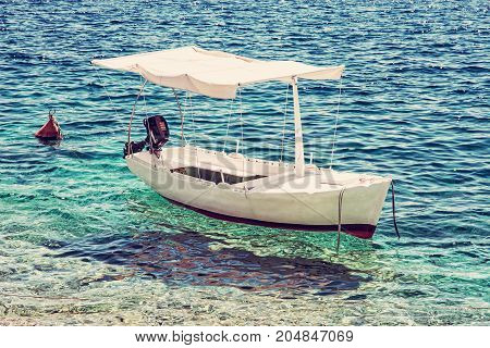 Anchored little boat in Maslinica Solta island Croatia. Summer vacation destination. Old photo filter.