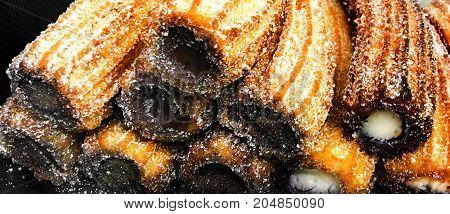 Churros on a market stall in a bakery shop. Sweet Famous Spanish dessert with chocolate sauce close up