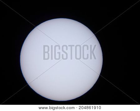 the sun viewed through a solar filter in a telescope with sunspot visible