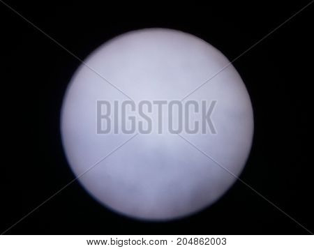 the sun viewed through a solar filter in a telescope with sunspot visible