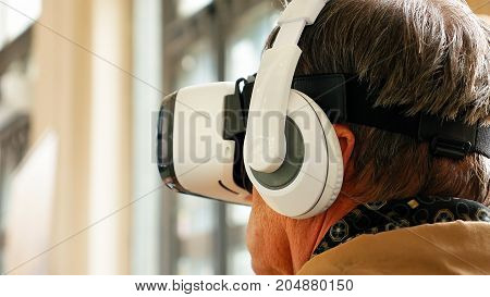 Senior old man wearing VR headset and enjoying virtual reality digital world. Virtual and augmented reality are increasingly used in human lives.