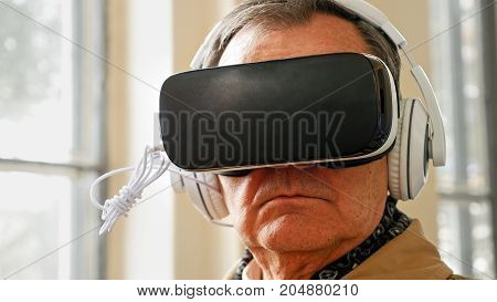 Senior old man wearing VR headset and enjoying virtual reality digital world. Virtual and augmented reality are increasingly used in human lives.