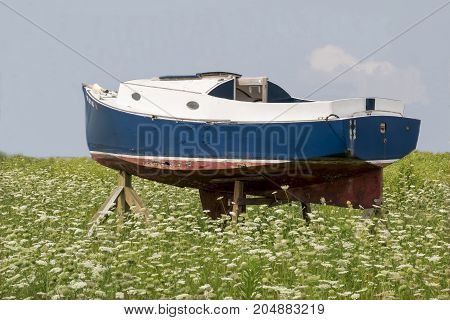 An old boat sitting in an open field.
